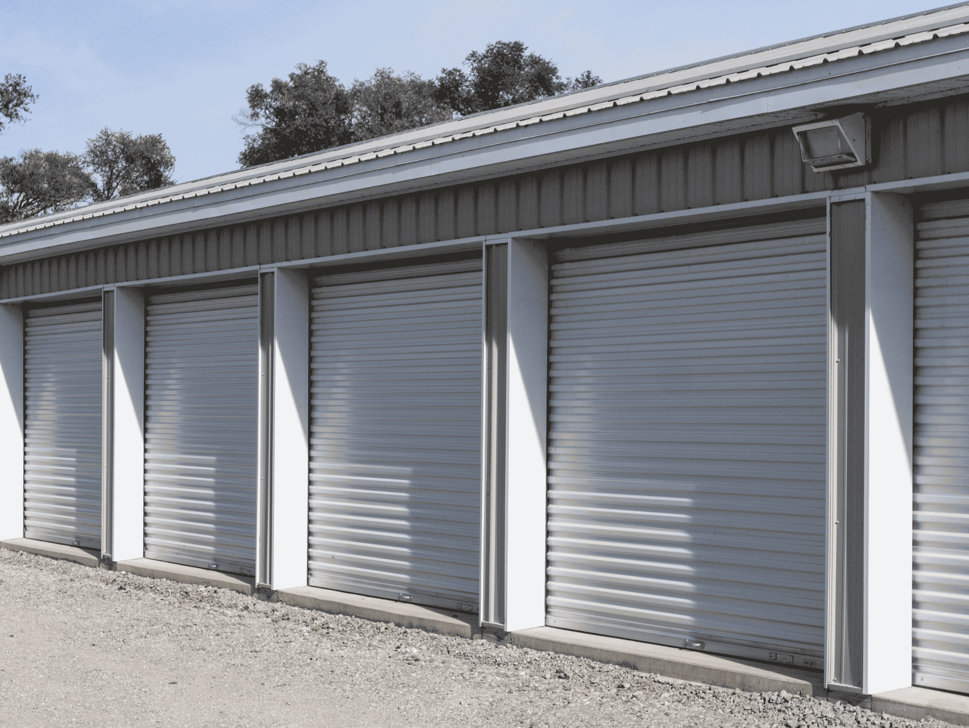 Row of secure self storage units with closed doors under a clear blue sky, providing safe and convenient storage solutions.